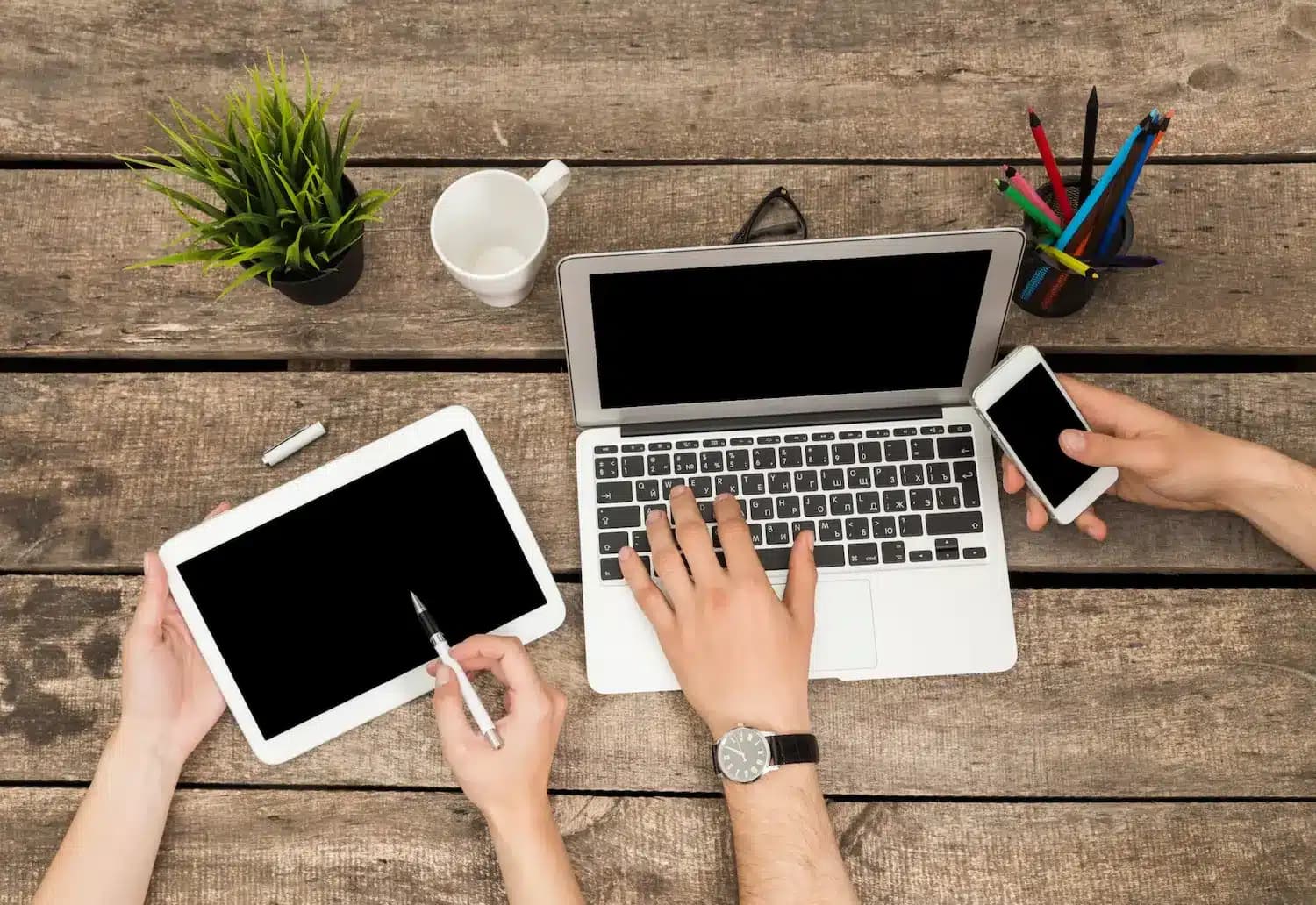 Gente joven colaborando con portatiles en una mesa de madera